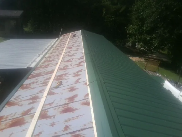 Old rusted panels beside newly installed green metal roofing — Wind Damage Roof Repair by Roofing Brothers in Alton