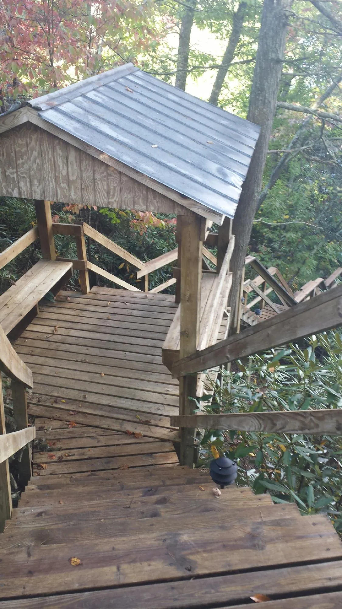 Metal roofed shelter over wooden steps on a wooded walkway — Skylight Repair & Installation work by our crew in Alton