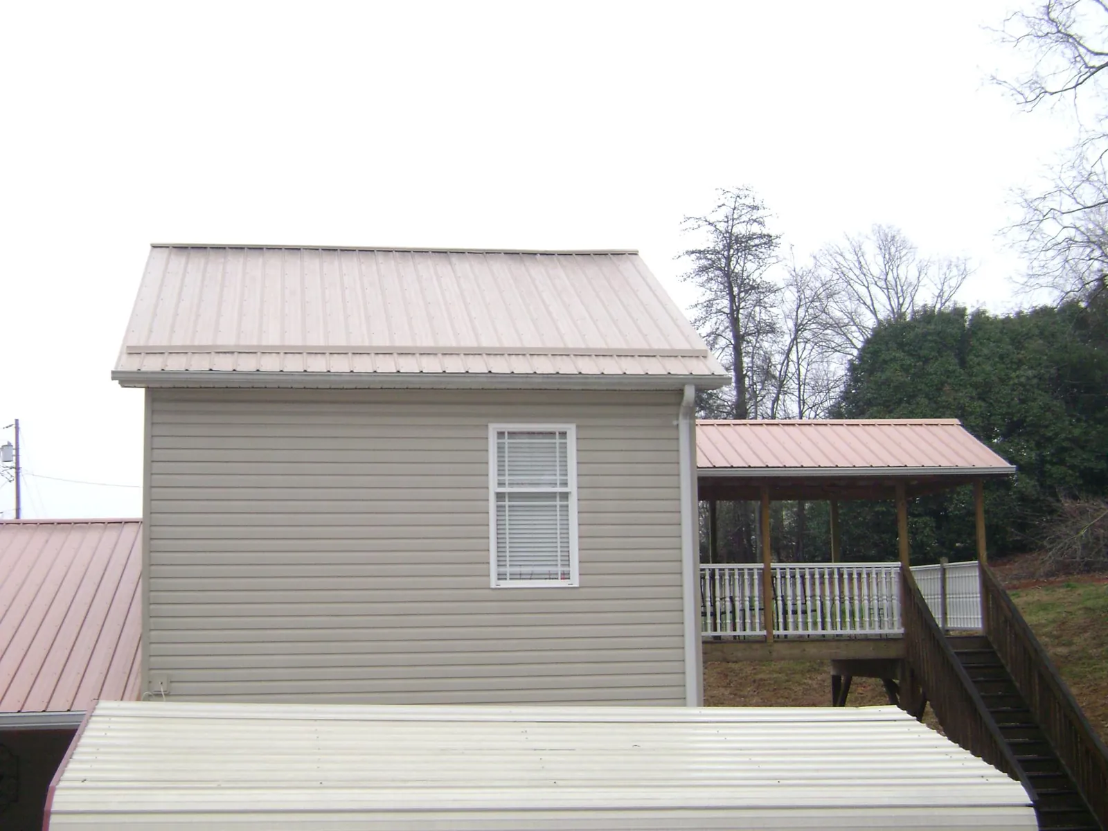 Tan metal roofs on a two story addition and attached porch in Alton